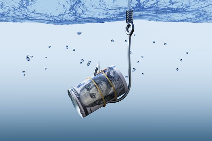 A fishing hook latches onto a roll of money under water. 