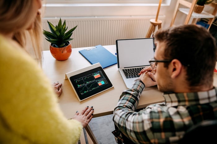 A couple looking at financial charts on a tablet.
