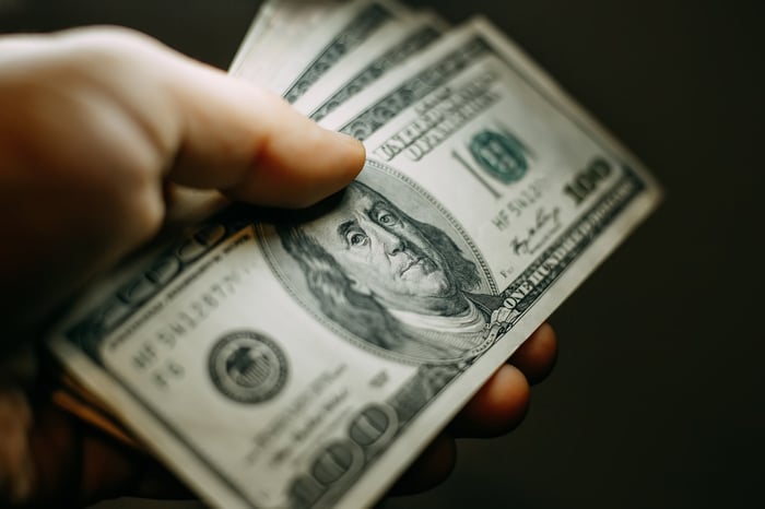 A hand holding $100 bills.