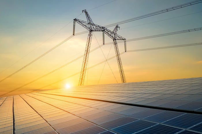 Power lines stretching out above a solar array as the sun sets.