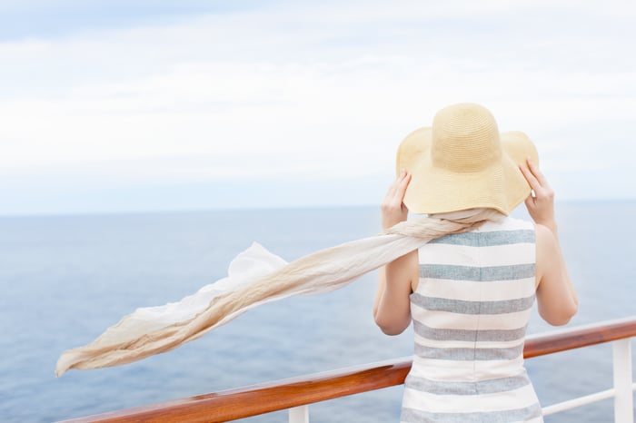 A passenger aboard a cruise ship looks out at the ocean.