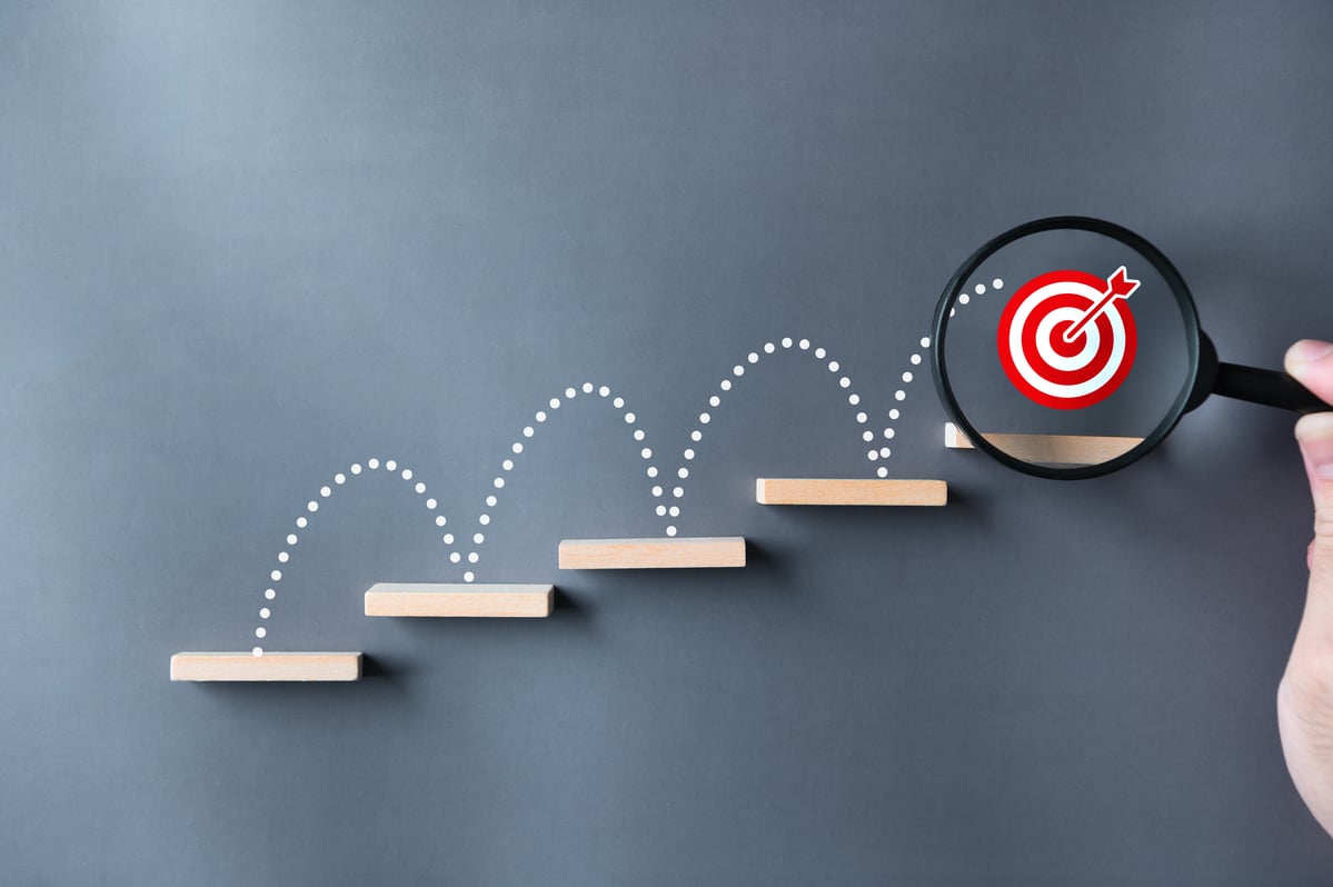 24_12_02 A bullseye jumping up stairs with a magnifying glass on it _MF Dload GettyImages-1511226415-1200x798-36b7a2e