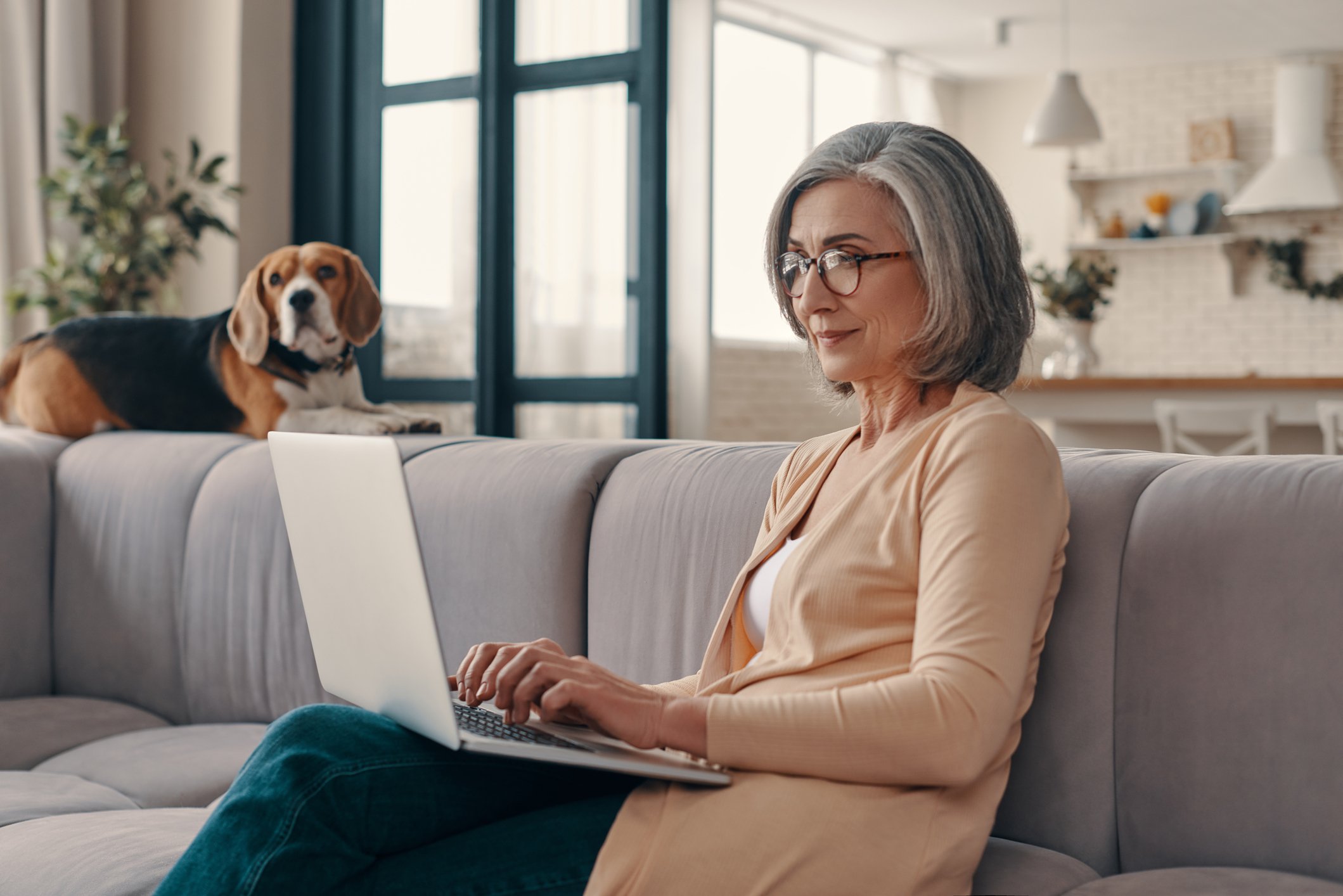 Older woman laptop dog in background GettyImages-1307241175