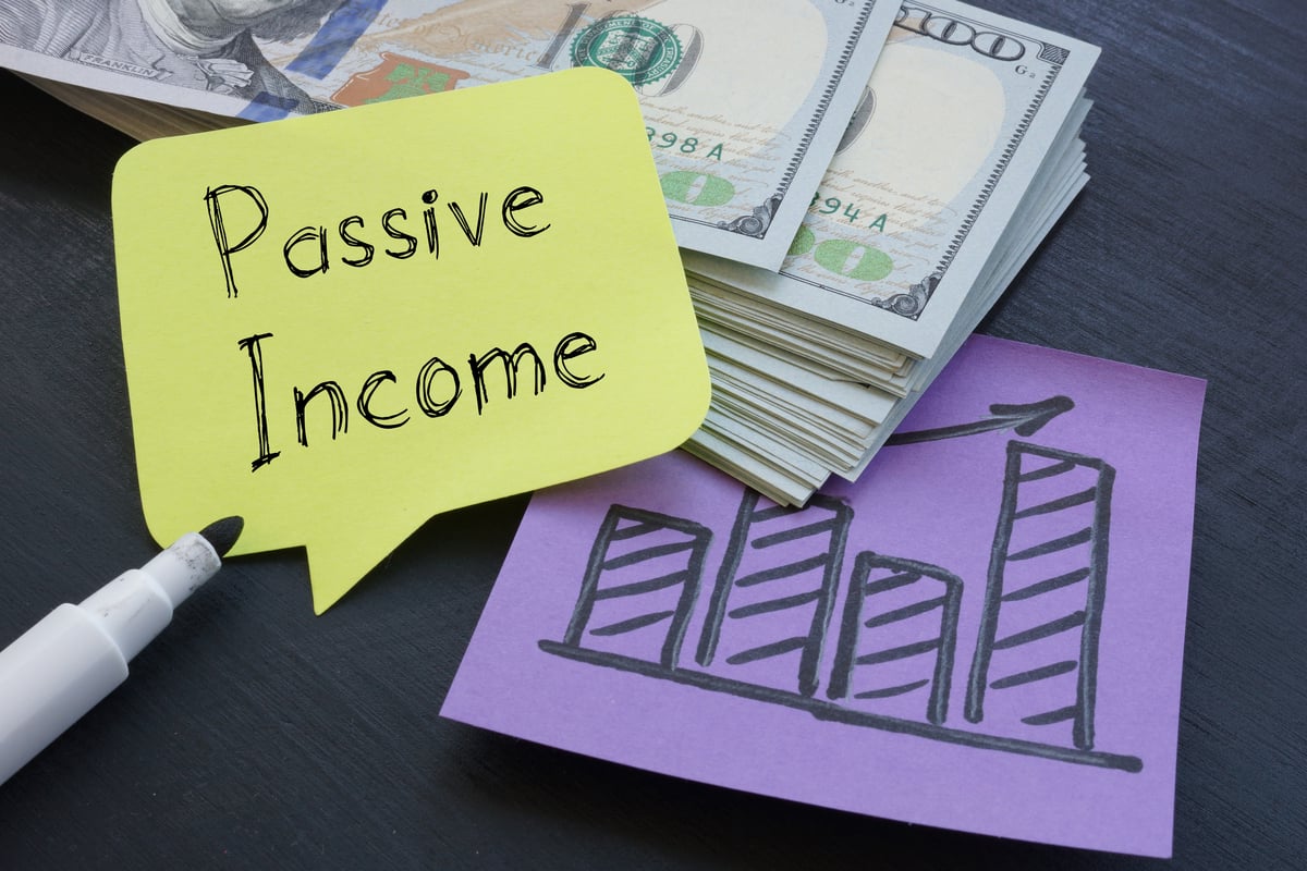 Passive income written on paper with a drawing of a bar chart and U.S. currency in the back