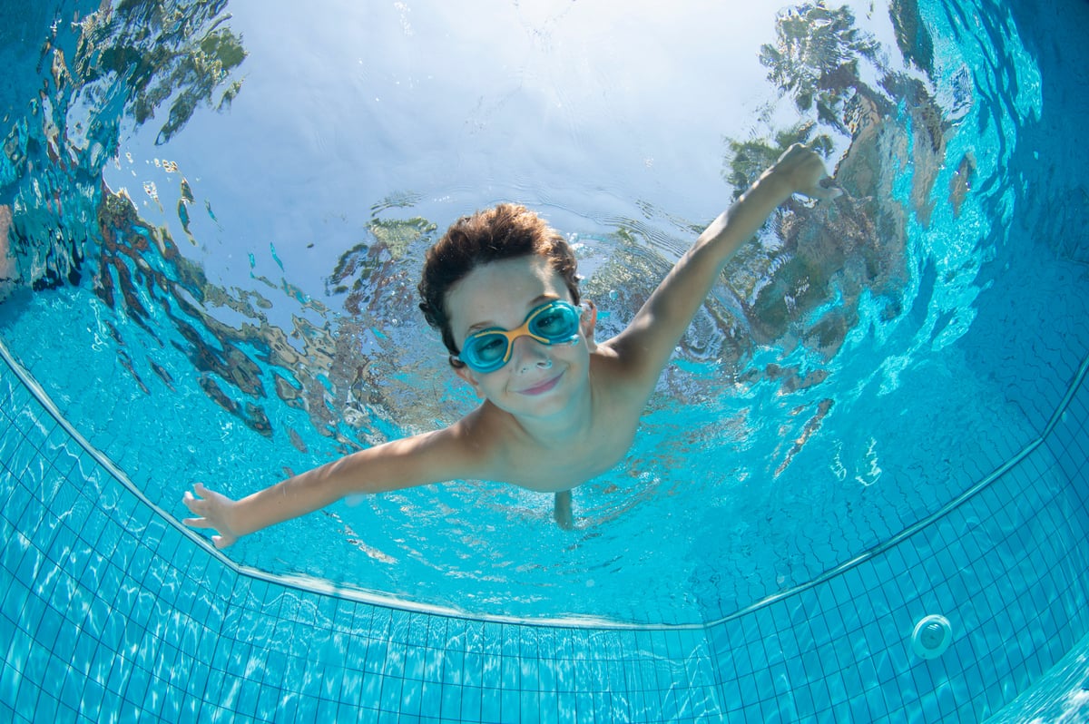 smiling boy swims underwater.