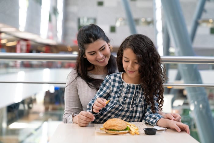 People eating a burger at a food court. 