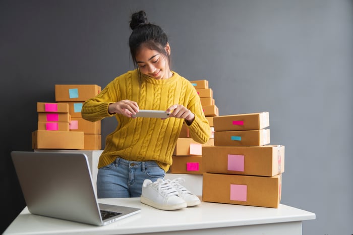 An online merchant takes a photo of a pair of shoes.