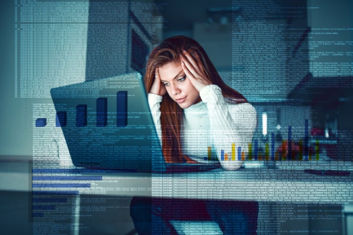 Exasperated person looking at a laptop computer in an office.