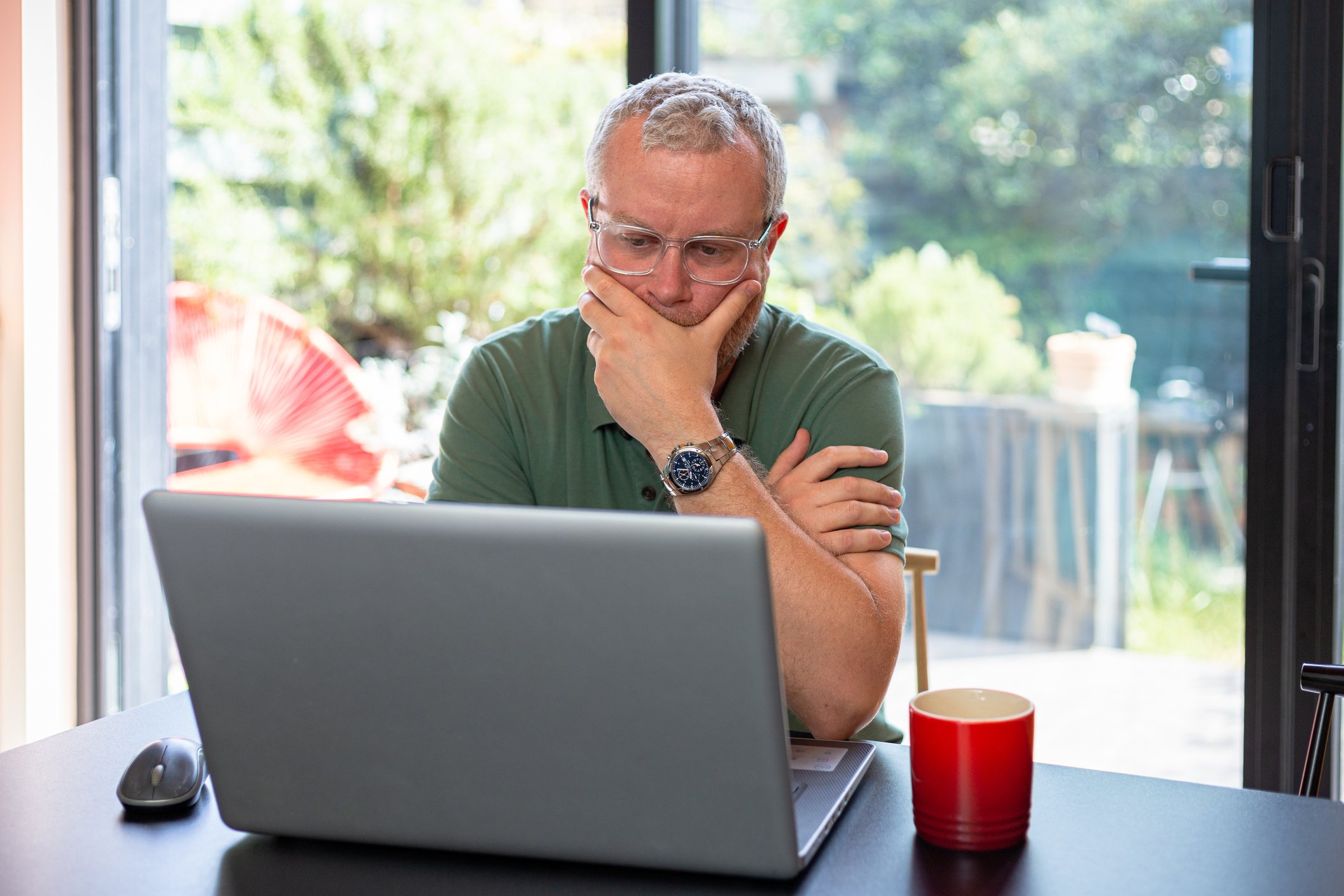 Man 40s laptop by window GettyImages-1403978354