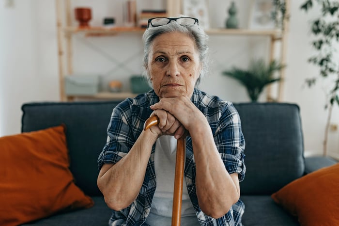 Someone leaning on a cane with a worried look.