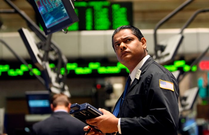 A New York Stock Exchange floor trader looking up in awe at a computer monitor.