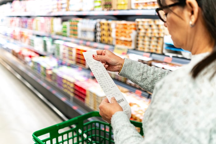 A shopper looking at a receipt in a store aisle.
