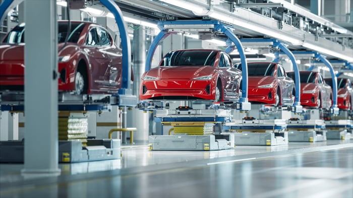 Electric vehicles (EVs) roll down the assembly line at an EV production facility.