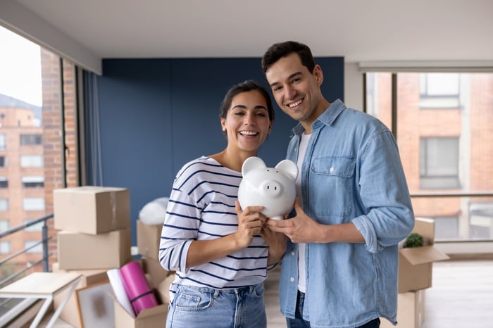 Two people standing up and holding a piggy bank together.