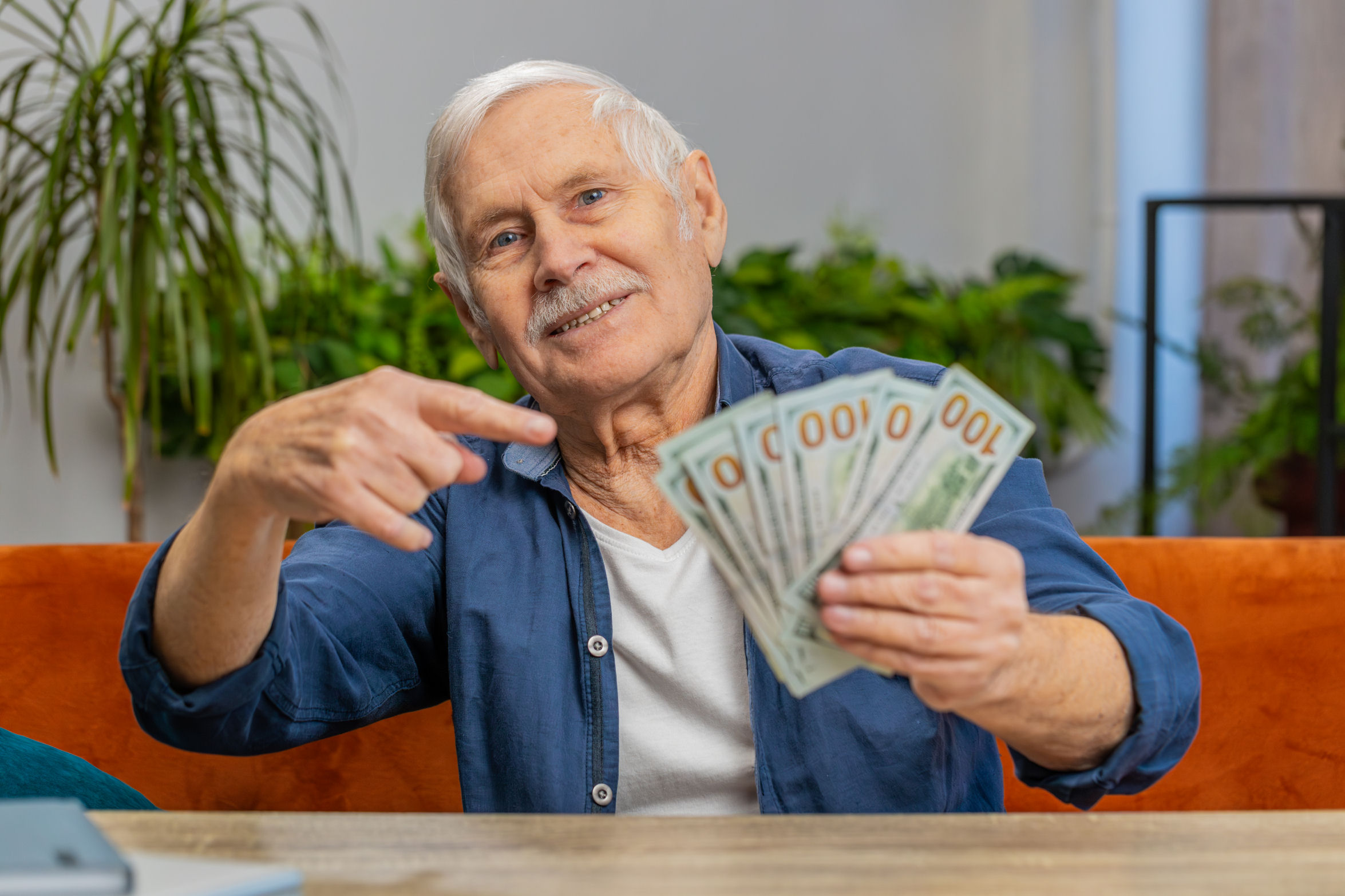 older investor holding several hundred dollar bills