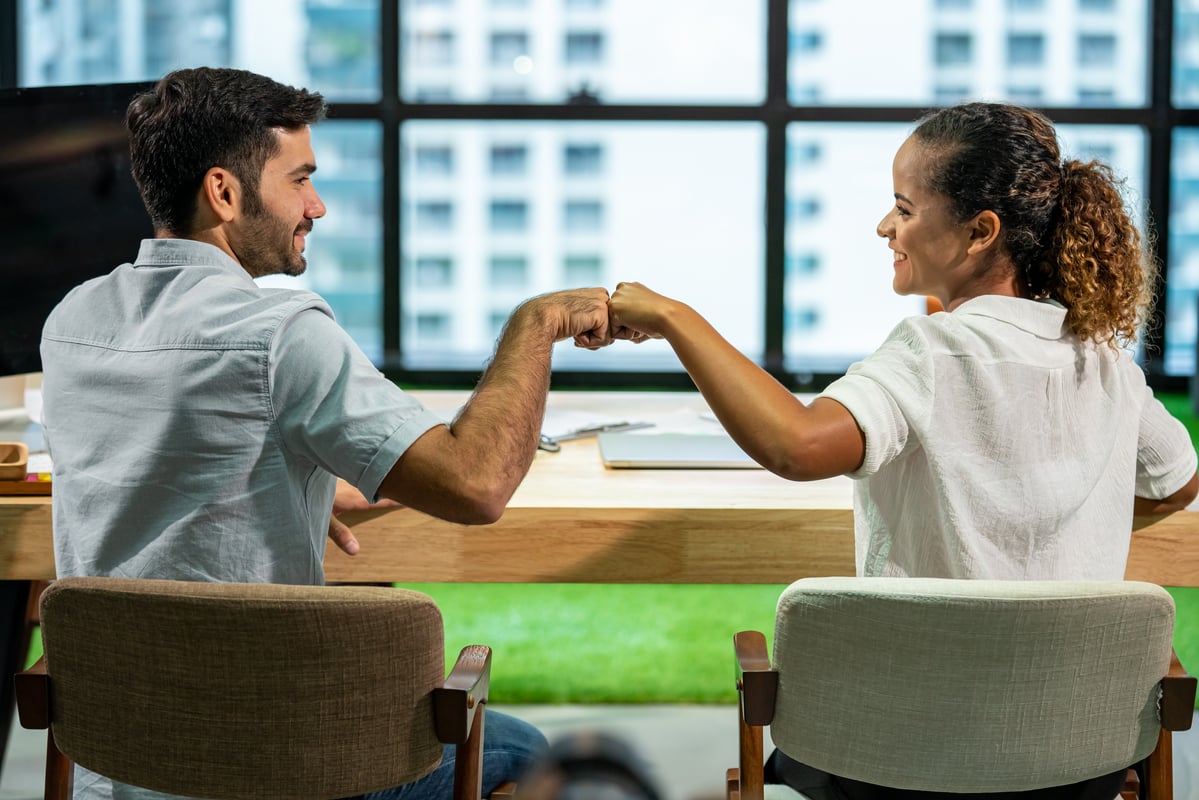 smiling investors fist bump.