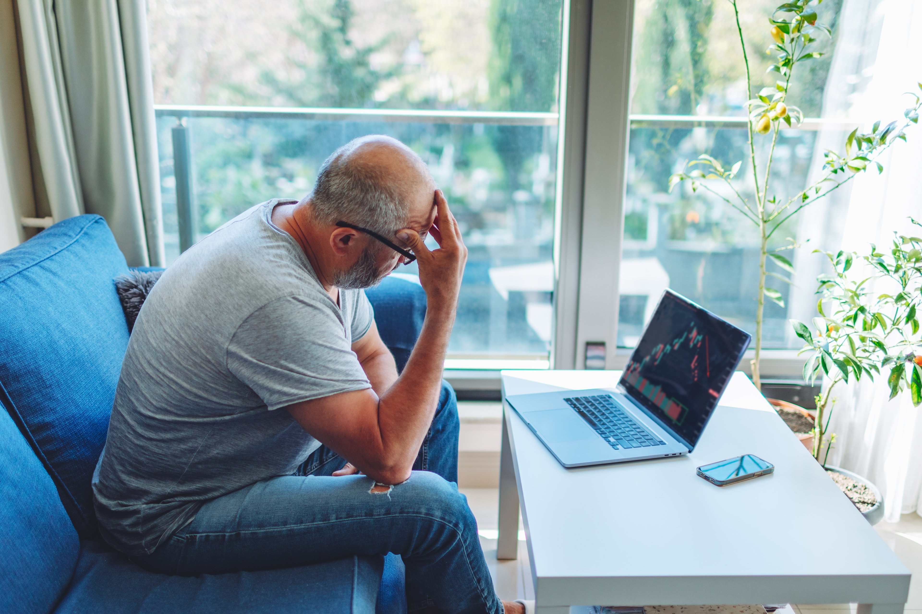 Person sitting in chair looking at a crashing stock price