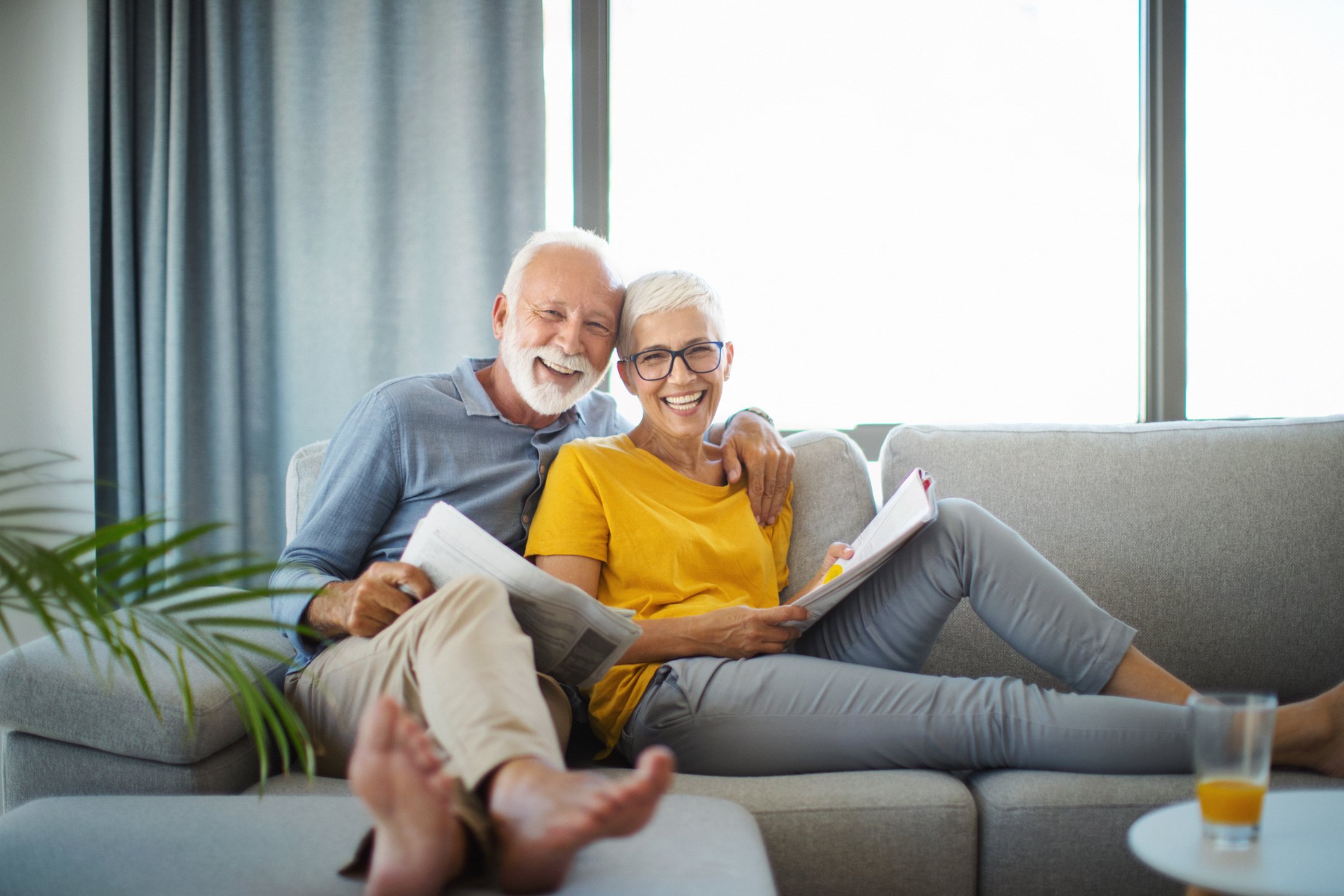 senior couple smiling on couch GettyImages-1202951876