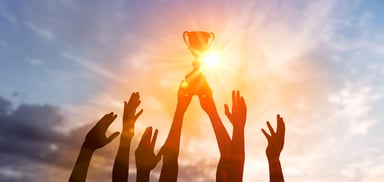 Many hands holding trophy in sunset 1477505250
