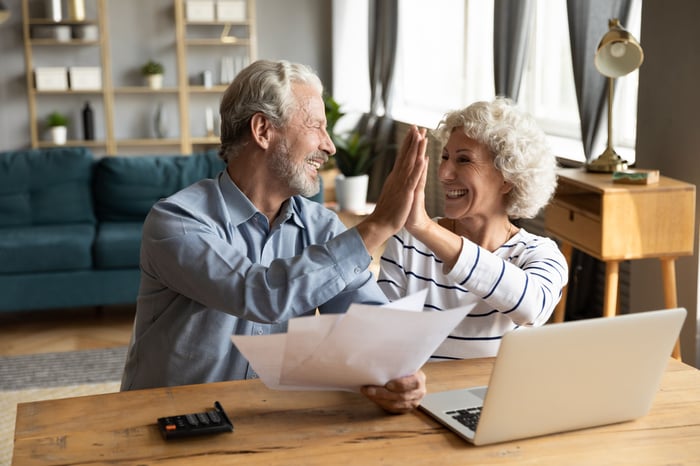A retired couple is high-fiving one another.
