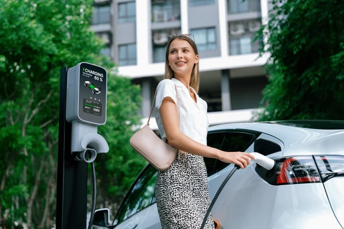 A driver plugs an electric car into a charger.
