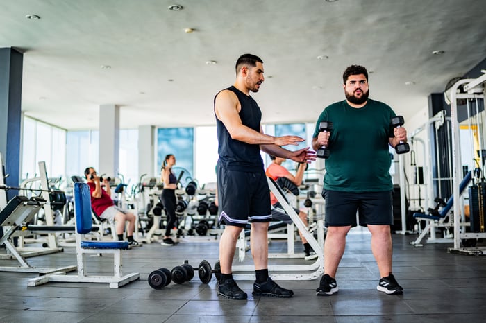 Two individuals work out in a gym.