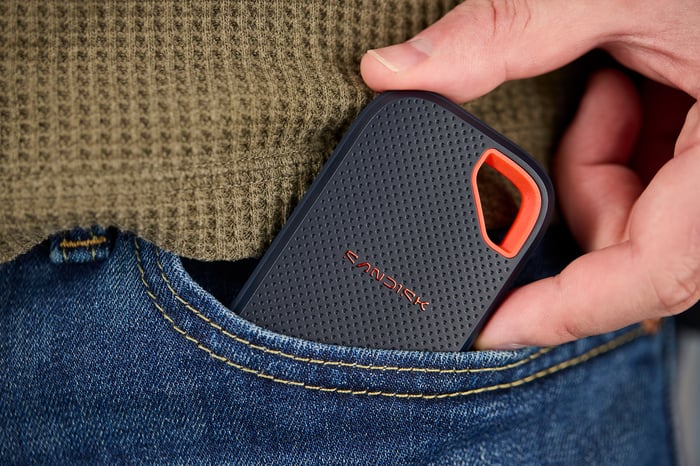 Person putting a Sandisk device in a jeans pocket.