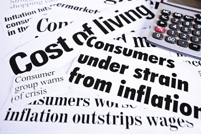 A calculator placed next to several newspaper-clipped headlines highlighting inflationary pressures.