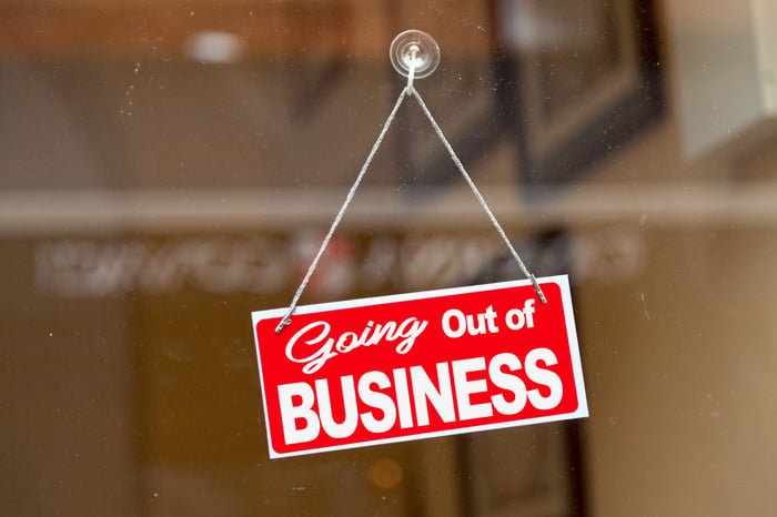 A going out of business sign hanging in a window.