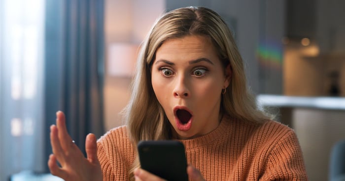 surprised investor looks at smartphone.
