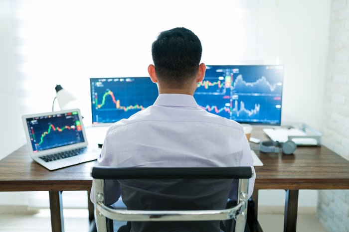A person working at a desk with multiple monitors.