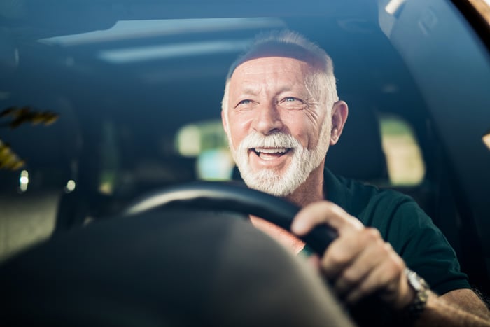 Someone is behind the wheel of a vehicle, smiling.