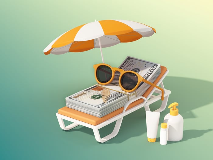 A wade of cash sits on an orange chair beside lotion. 