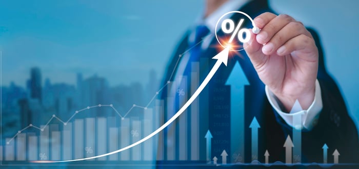 An individual in a suit points up an arrow with a percentage on it. 