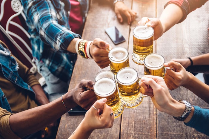 Hands holding beer glasses above a table.