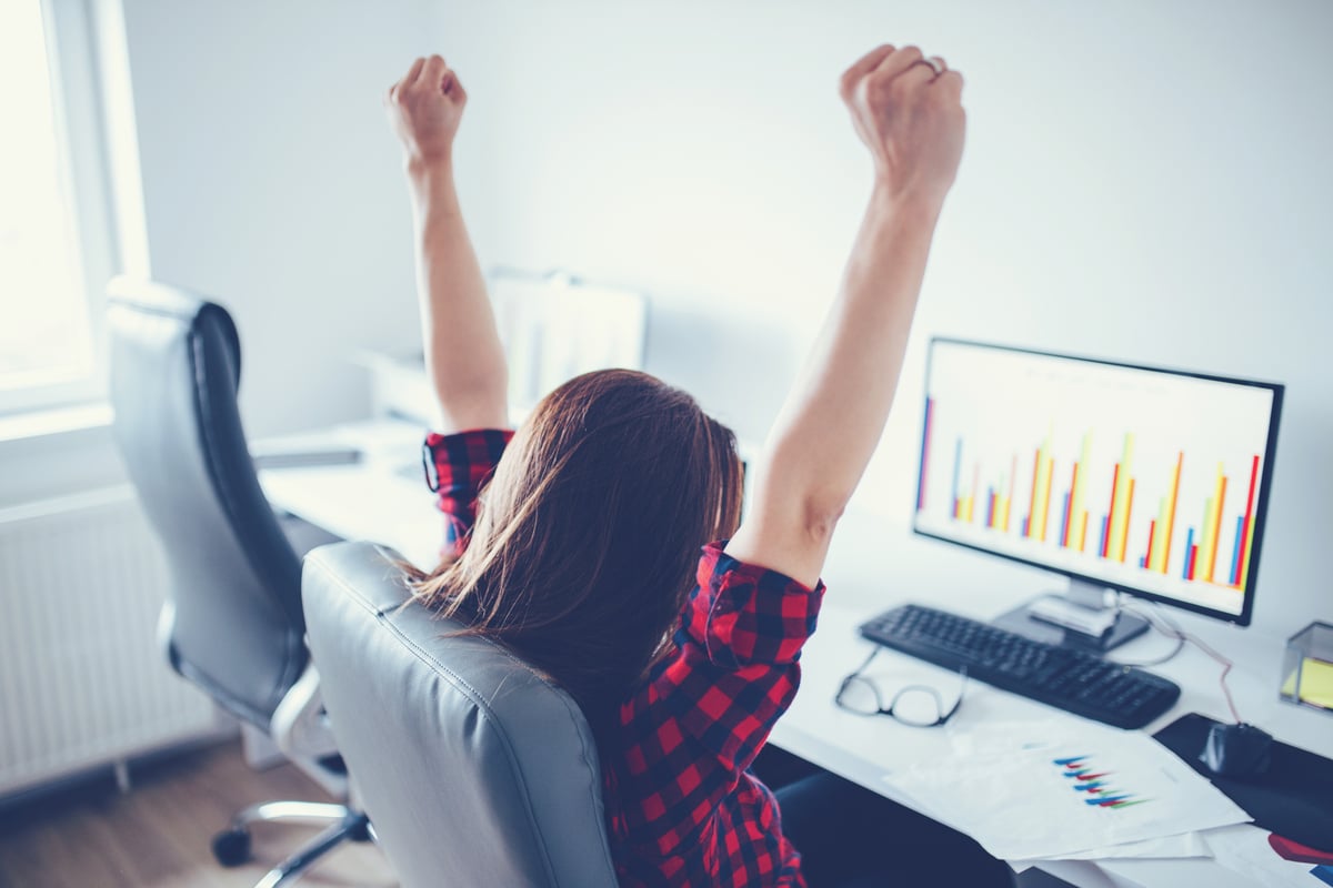 celebrating investor works on desktop computer.