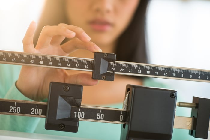 Person adjusting weights on a body scale.