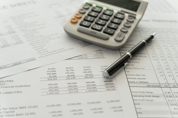 A calculator and pen on top of financial papers. 