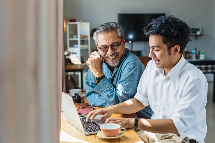 A middle-aged father talks with his young adult son about investing in a 401(k).