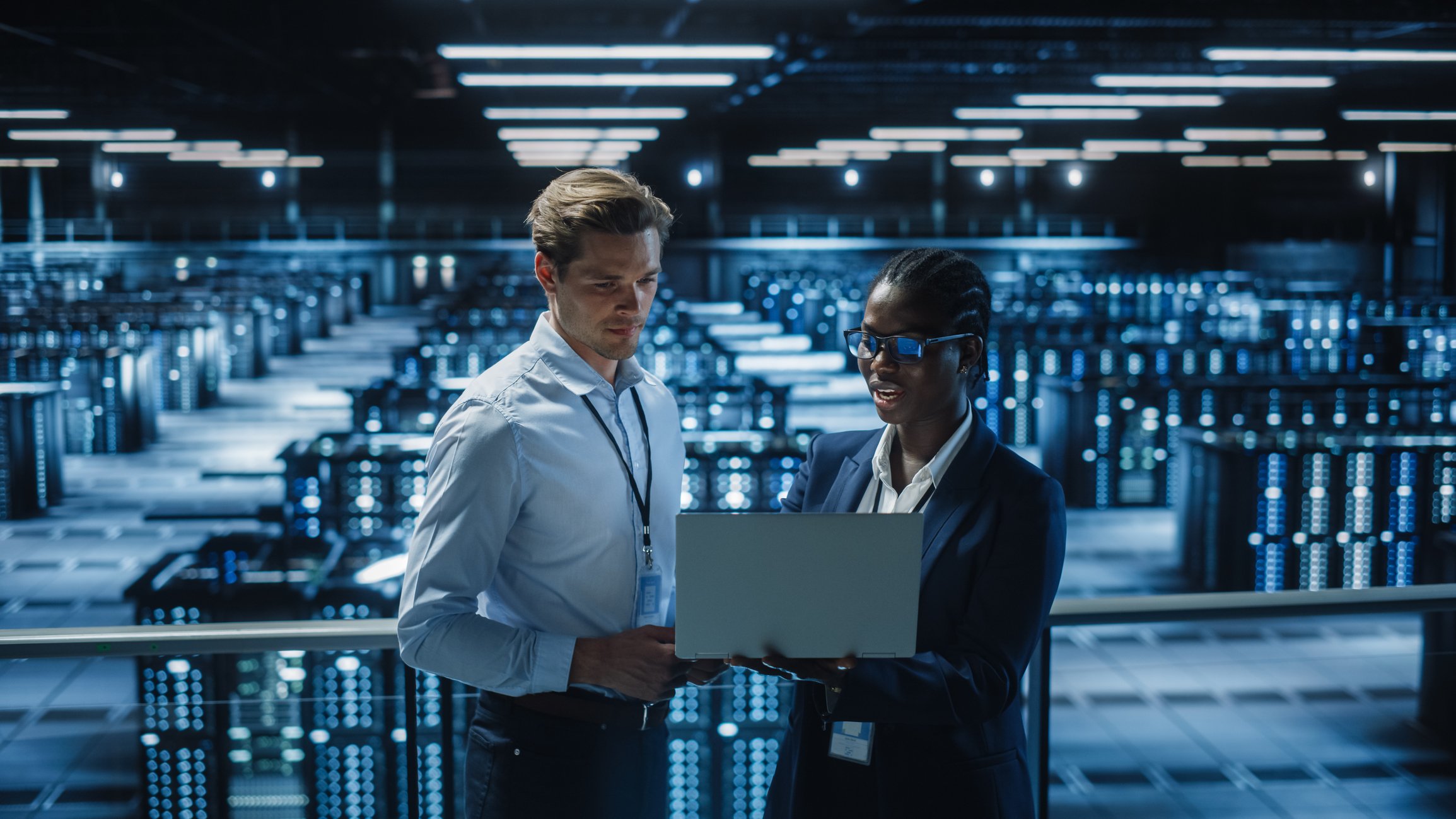 two engineers looking at a computer in a data center