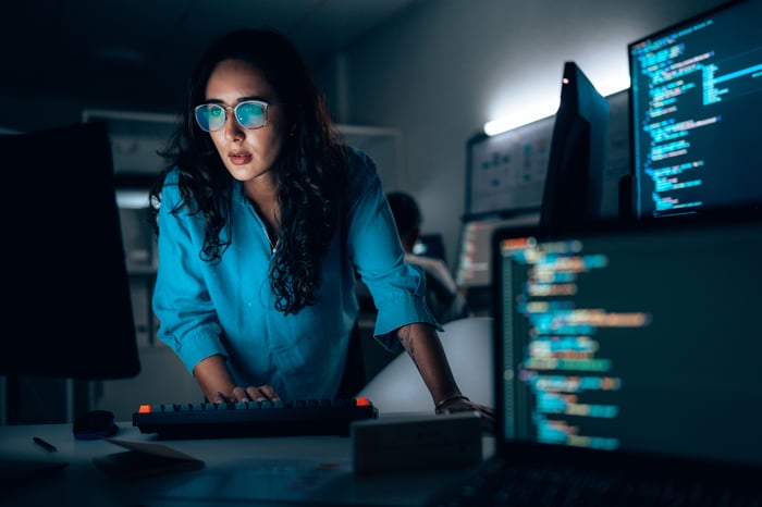 An investor checks multiple screens in a dim office.