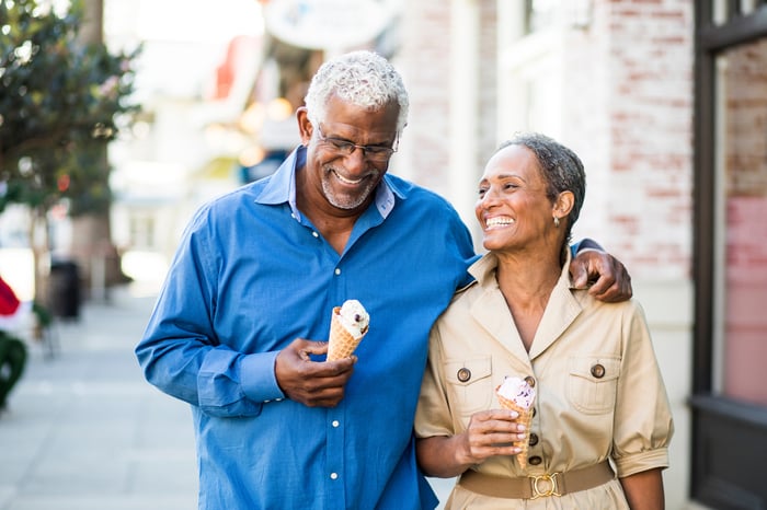 Smiling couple walking down the street eating ice cream.