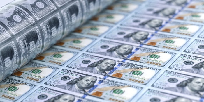 Hundred-dollar bills rolling out of a printing press.