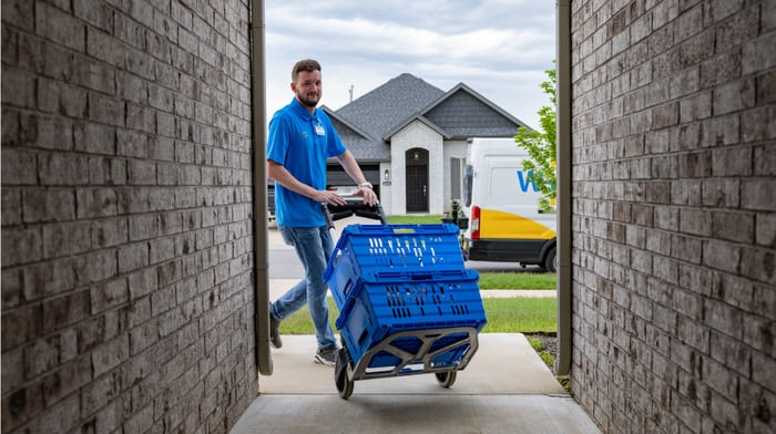 A Walmrt delivery person bringing an order to a house.