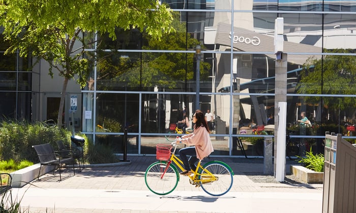 A person rides a bike in front of a building at Google.