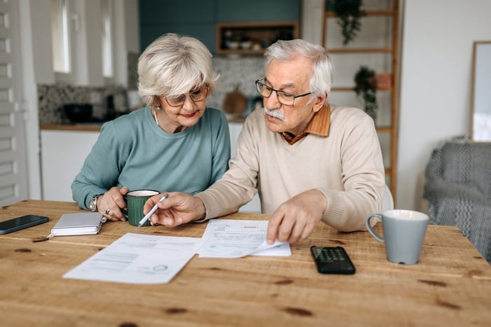 Two people sitting at their kitchen table, going over paperwork together. 