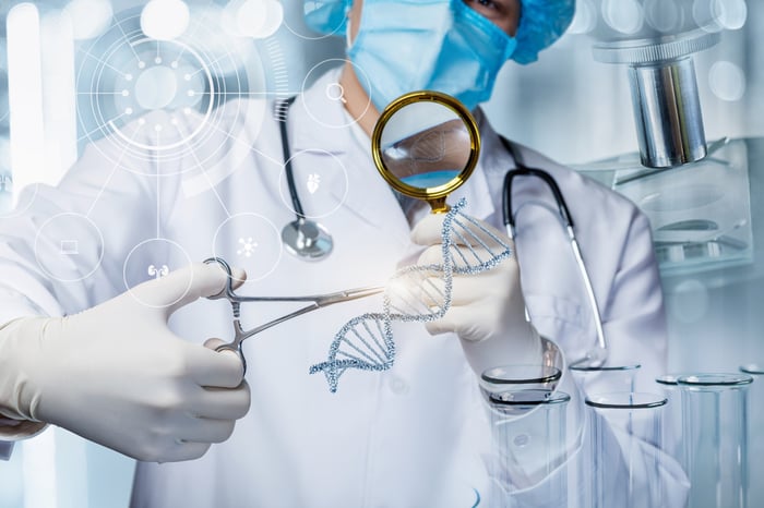 Medical technician appearing to modify the DNA of a cell with scissors and a magnifying glass. 