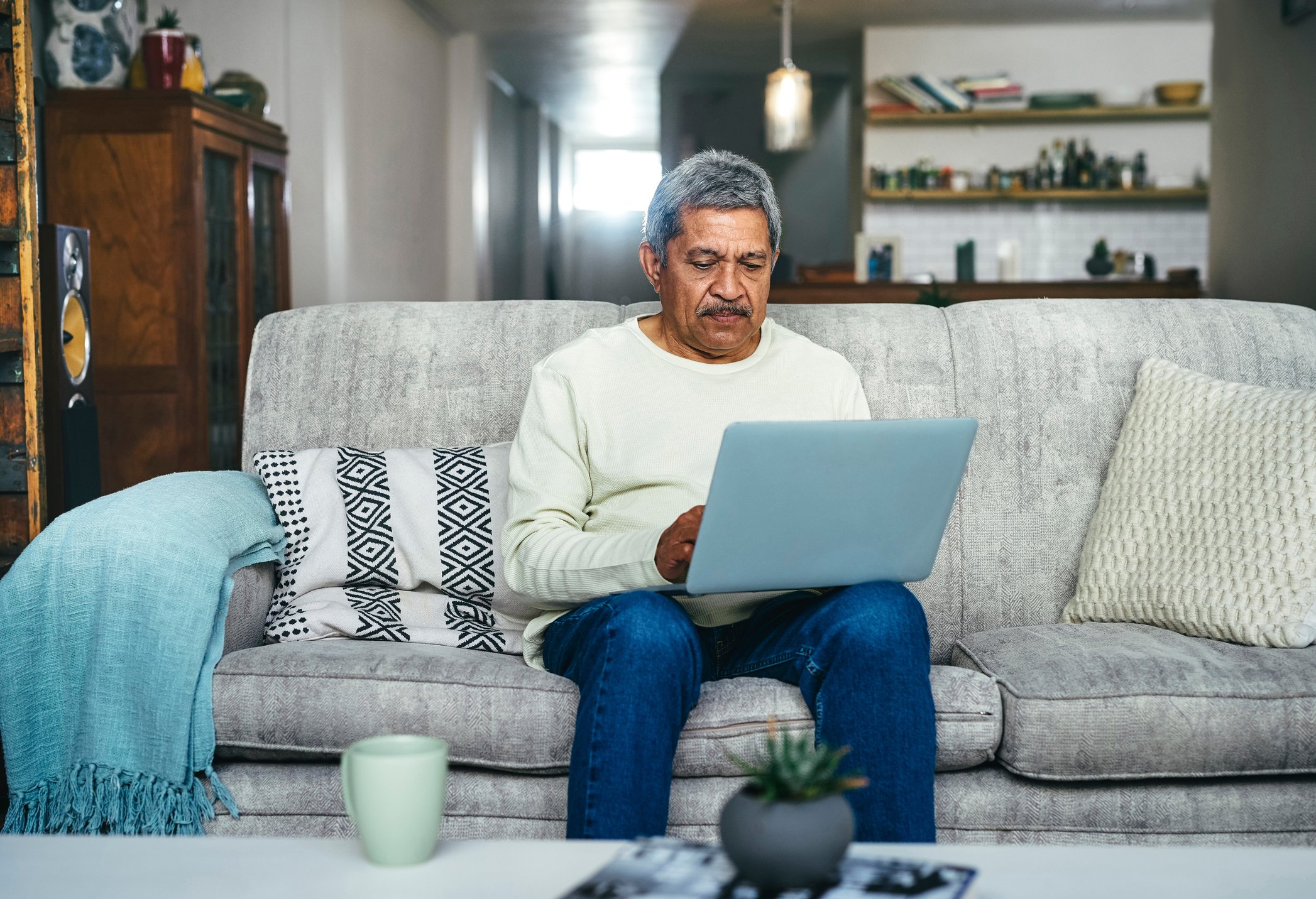 Senior man A person using a laptop on a couch_GettyImages-1357522262
