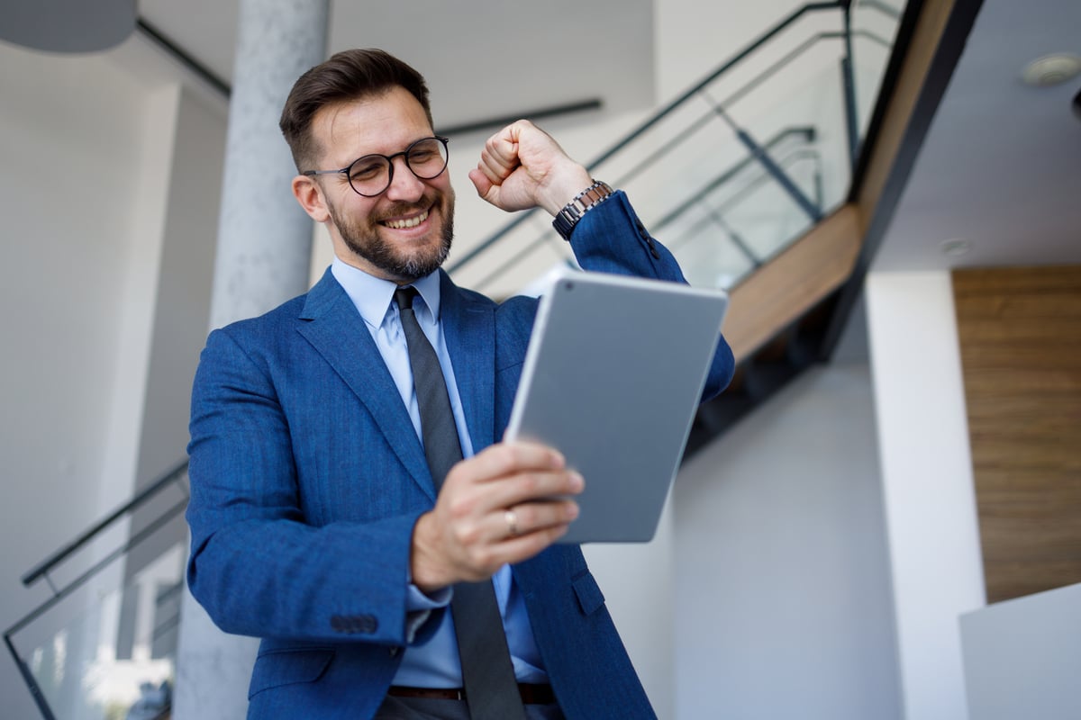 investor looks at tablet and celebrates.