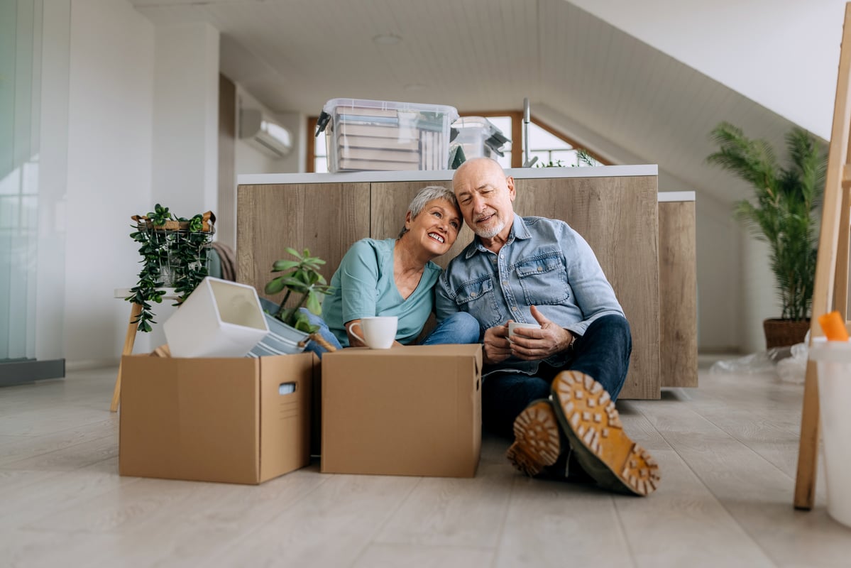 Couple sitting on floor of apartment surrounded by boxes